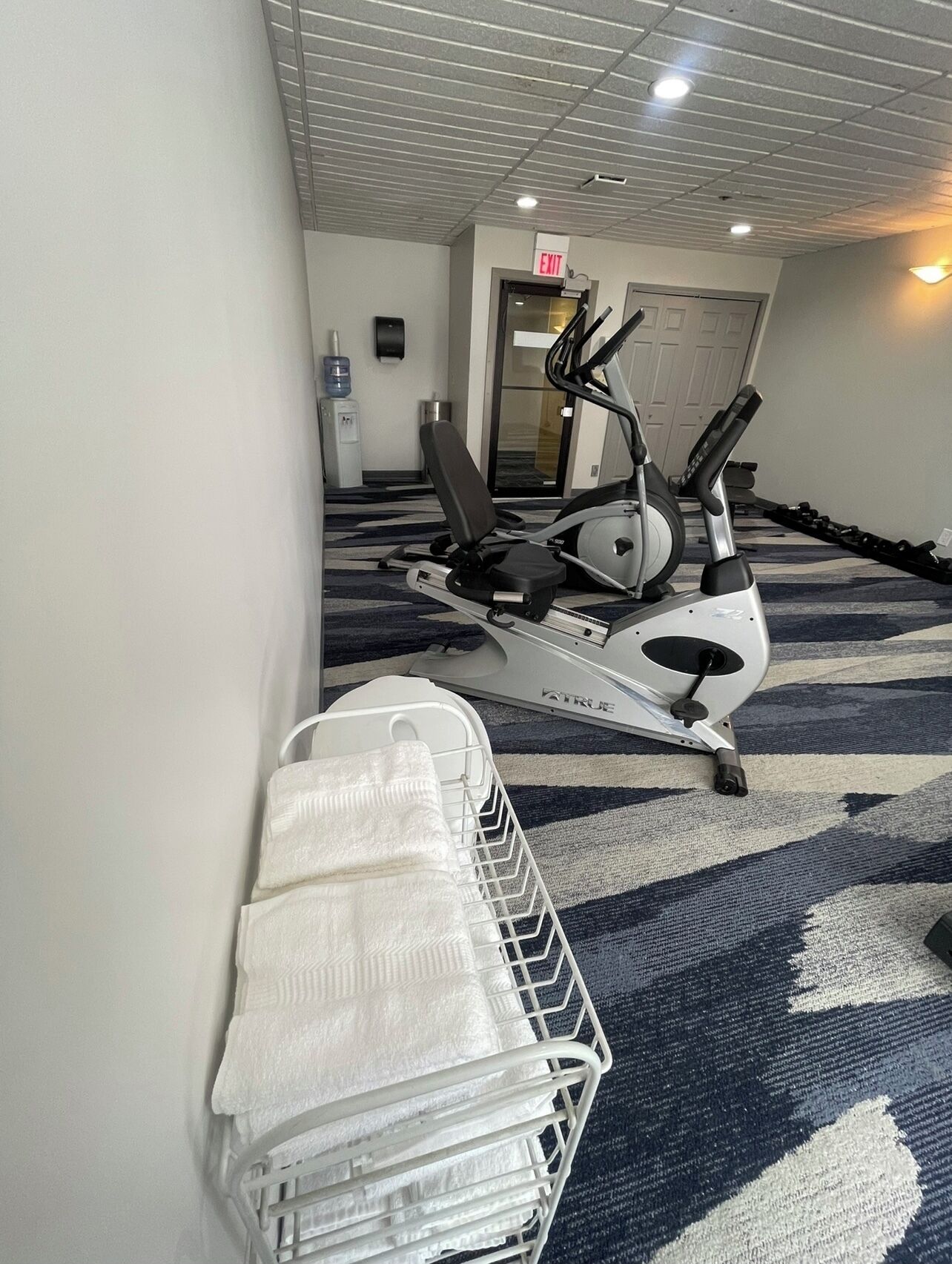 A fitness area with exercise equipment, a water dispenser, and a towel rack.