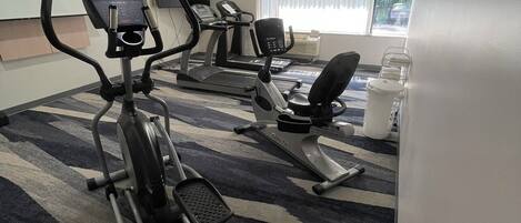 A gym with treadmills, elliptical machines, and a stationary bike.