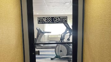 Puerta que da a un gimnasio, donde se ven cintas de correr y elípticas.