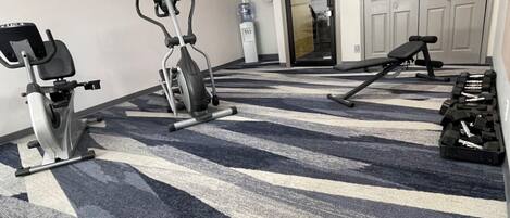 A gym with exercise equipment including treadmills, stationary bikes, and a bench.