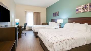 A hotel room with two beds, a desk, a chair, a TV, and a window with curtains.