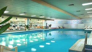 An indoor swimming pool with clear blue water, surrounded by lounge chairs and potted plants. - Hotel New Century Beijing (Beijing)