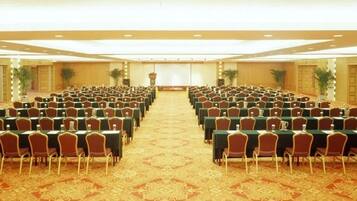 A conference room with rows of tables and chairs, a carpeted floor, and a podium at the front.