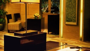 A modern hotel room with a large table, a lamp, a chair, and a city view. - Hotel New Century Beijing (Beijing)