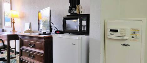 Habitación de hotel con escritorio, microondas, refrigerador y termostato.