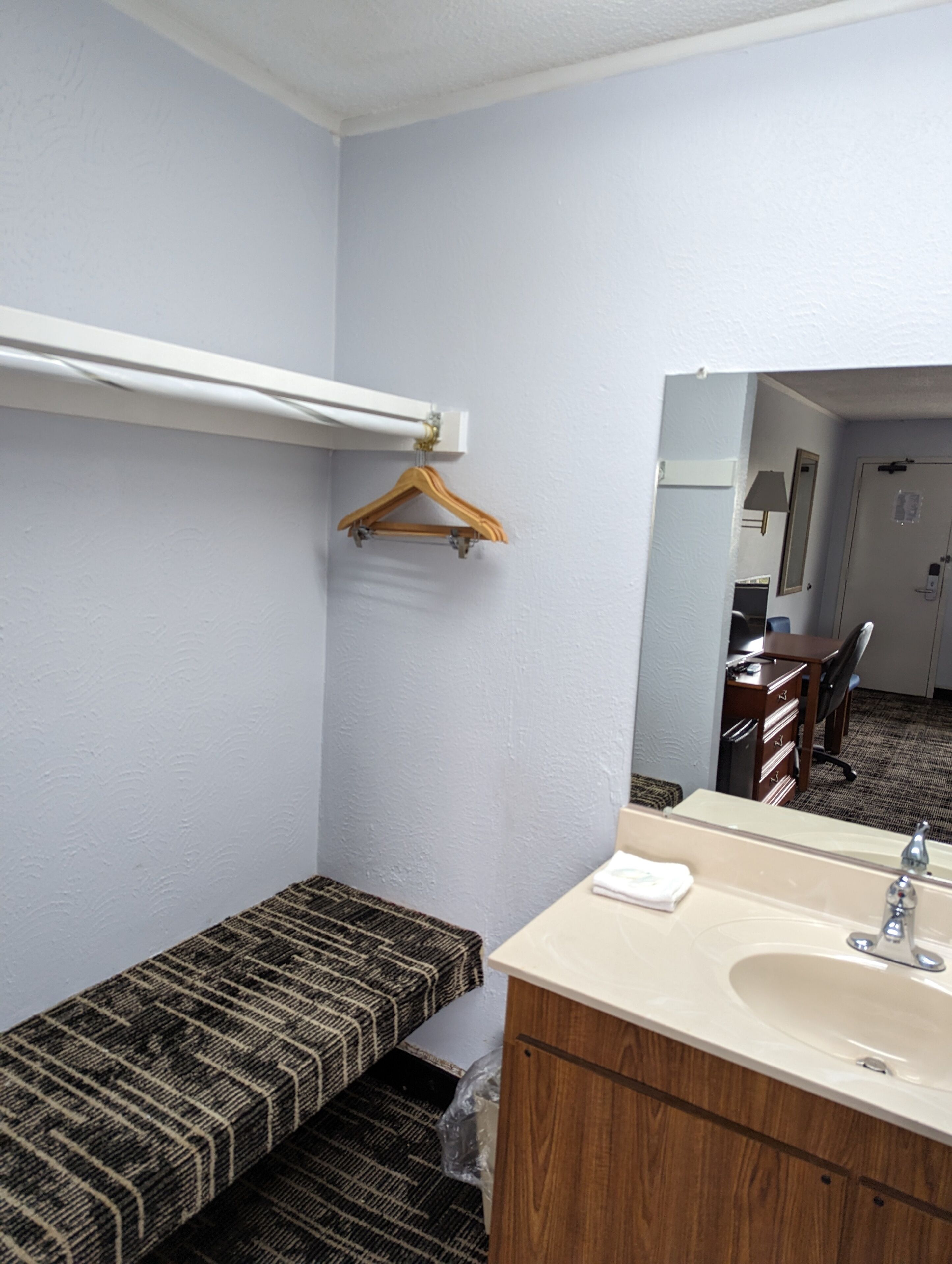 A small bathroom with a wooden bench, a sink, and a mirror.
