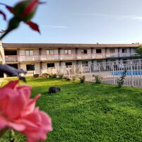 Ein mehrstöckiges Motel mit Schwimmbad, gepflegtem Rasen und einem Balkon an jeder Etage.