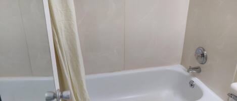 Un baño con bañera, cortina de ducha y retrete.