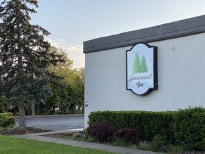 A building with a sign that reads "Sprucewood Inn" and a parking lot in the background. - Sprucewood Inn (Elyria)