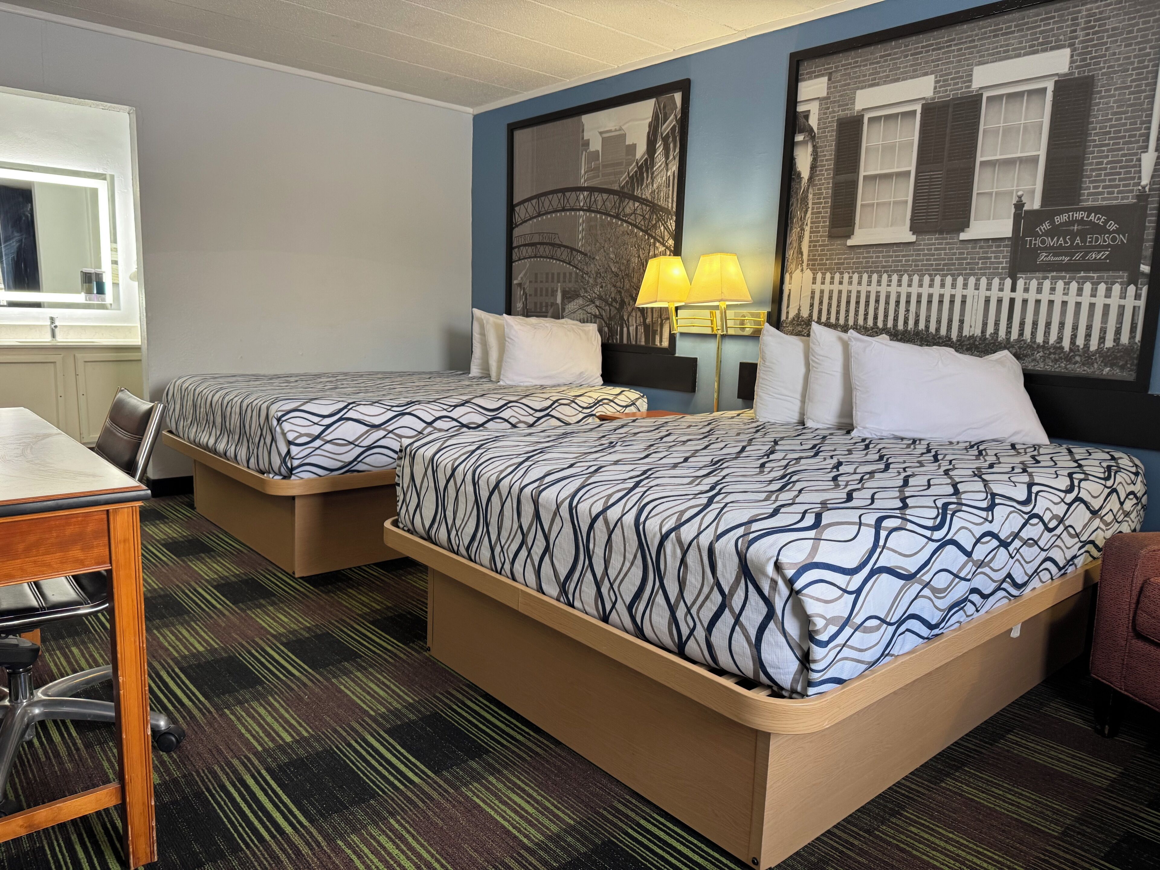 A hotel room with two beds, a desk, and a chair.