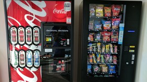 Two vending machines, one with Coca-Cola and the other with snacks.