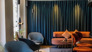 A modern living room with a sofa, chairs, and a curtain backdrop. - Motel One Copenhagen (Copenhagen)