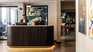 A reception desk with two computers, a modern interior, and a view of the city through large windows. - Motel One Copenhagen (Copenhagen)