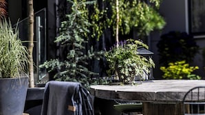 An outdoor seating area with a round table, chairs, and potted plants. - Motel One Copenhagen (Copenhagen)