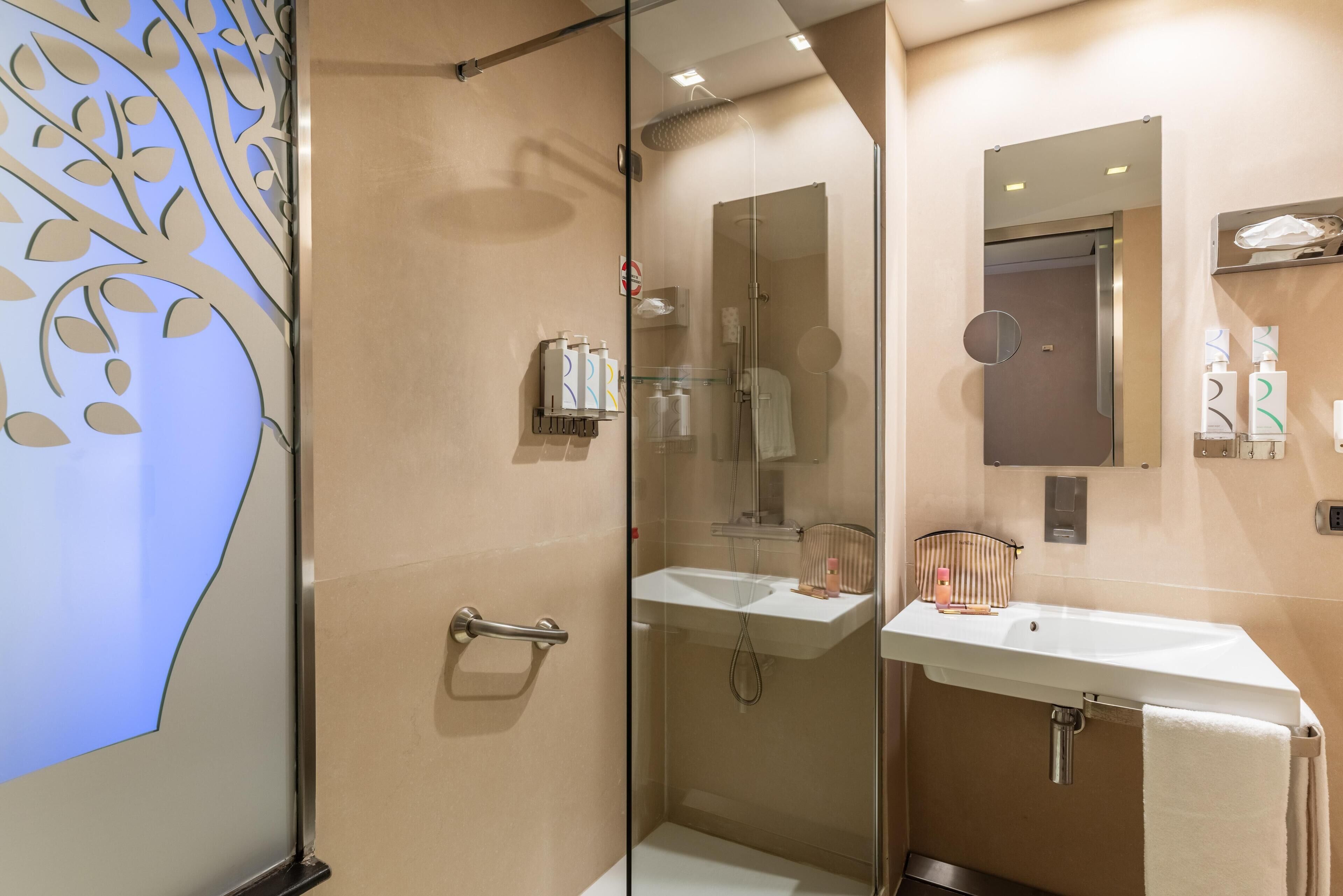 A modern bathroom with a glass shower enclosure, a sink, and a mirror.