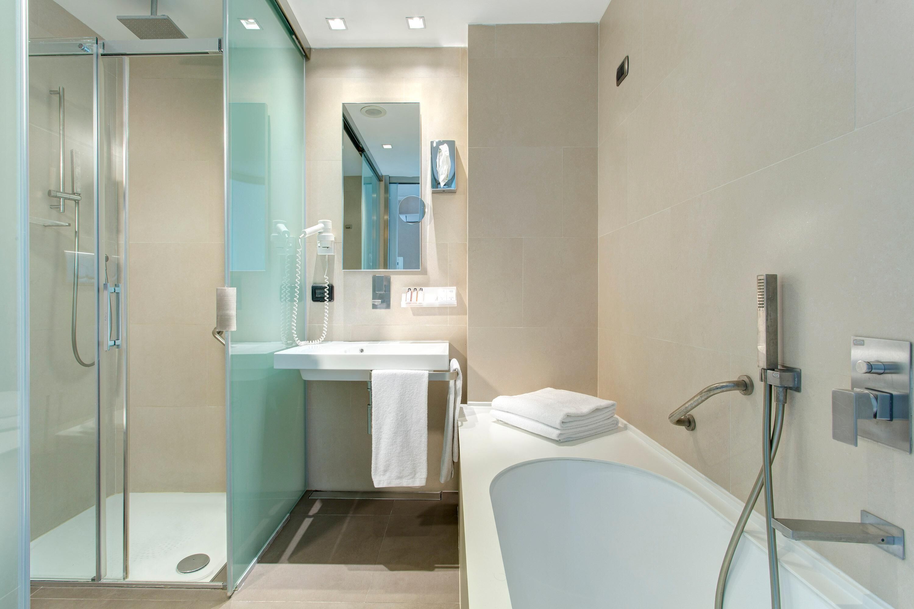 Une salle de bain moderne avec une douche à parois de verre, un lavabo blanc et une grande baignoire.