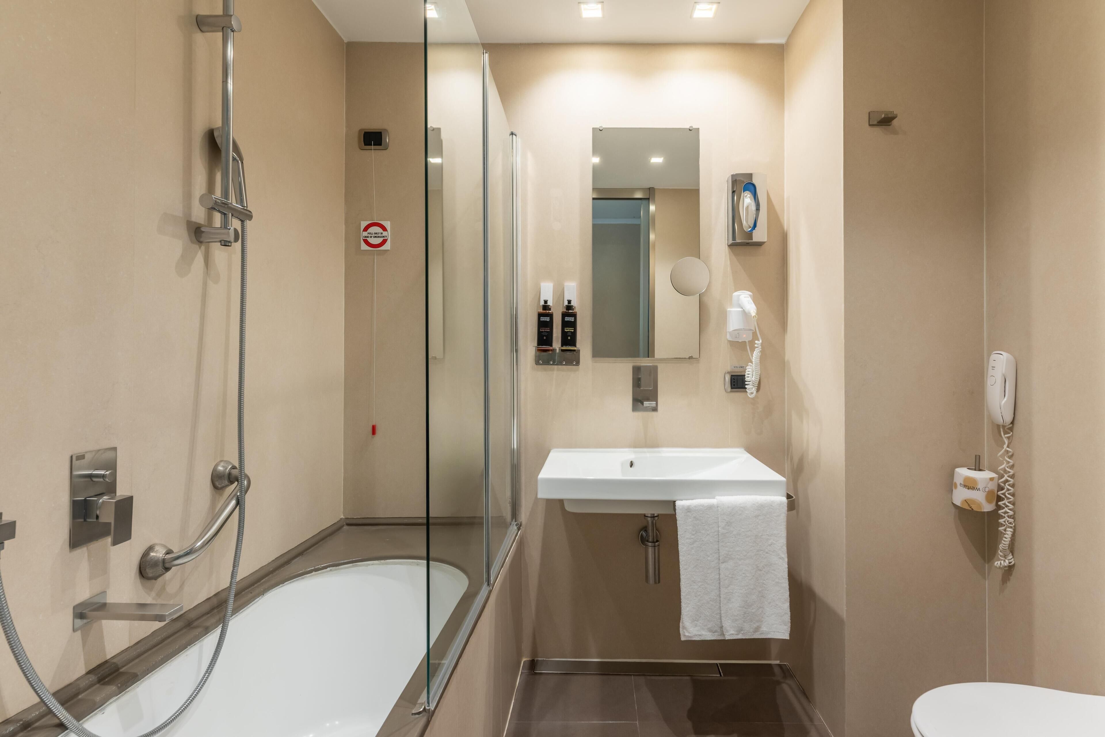 Une salle de bain moderne avec une douche à parois de verre, un lavabo blanc, un miroir et des toilettes.