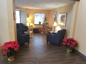 Una sala de estar con dos sillones, una mesa de centro, un árbol de Navidad y plantas de poinsettia.