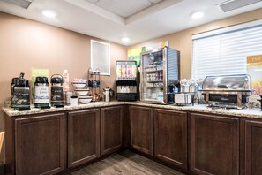 A self-service coffee station with various coffee machines, a refrigerated display, and a hot food display.