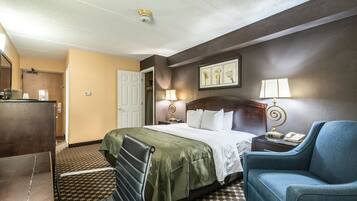 Ein Hotelzimmer mit einem Bett, zwei Nachttischen, einem Sessel, einem Schreibtisch und einem Spiegel.