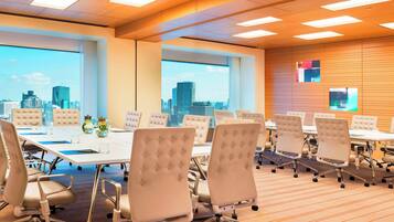 A conference room with a city view, white tables, and chairs.
