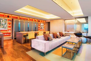 A modern living room with a sofa, coffee table, and a dining area with chairs.