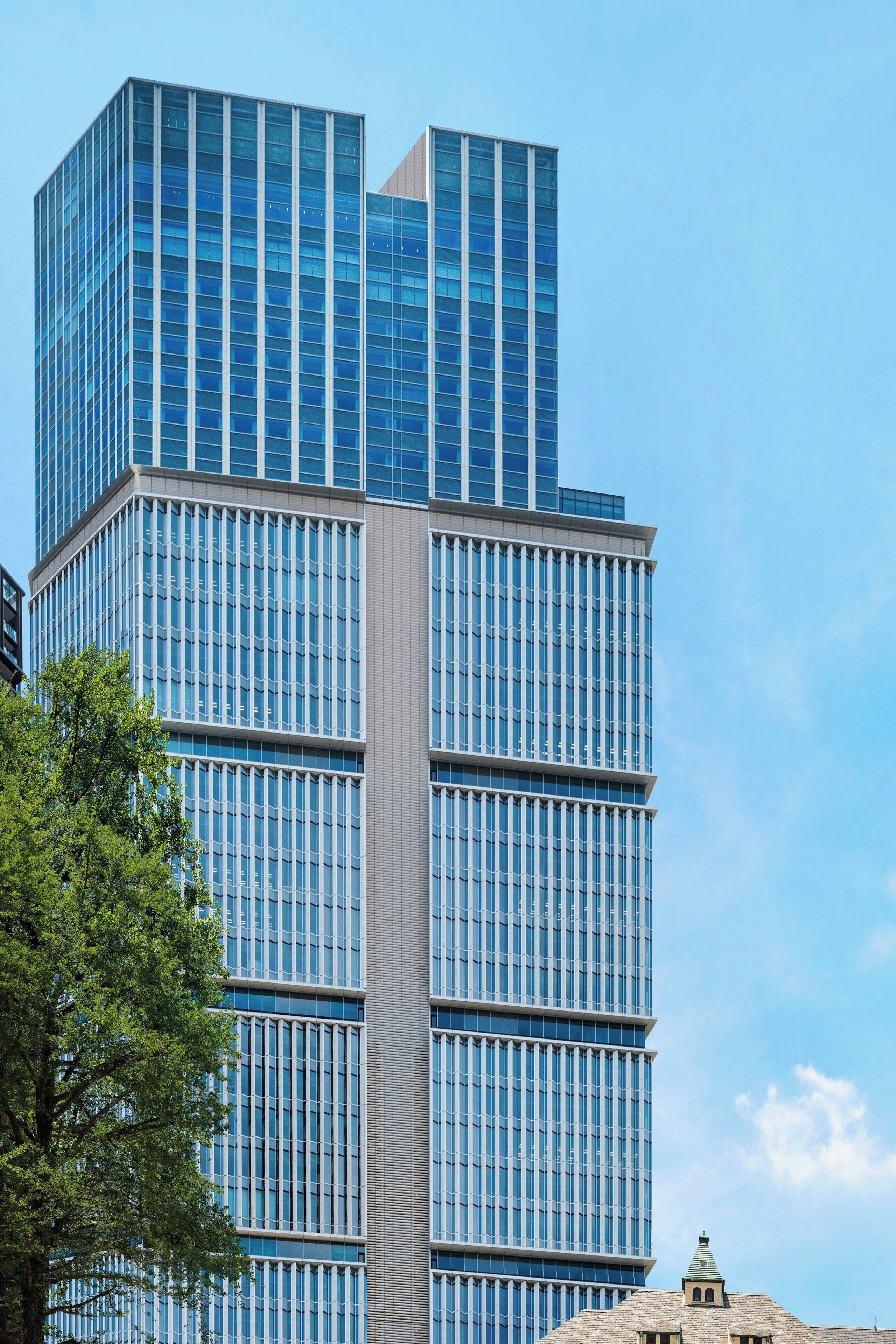 A modern high-rise building with a glass facade and a central vertical structure.