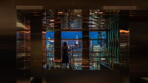A woman standing in a modern lobby with a cityscape view through a large glass window. - The Prince Gallery Tokyo Kioicho, a Luxury Collection Hotel (Tokyo)