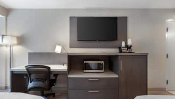 Una habitación de hotel moderna con televisión de pantalla plana, microondas, escritorio con silla y cama.