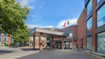 Un edificio moderno con un ingresso coperto, ampie finestre e una bandiera.