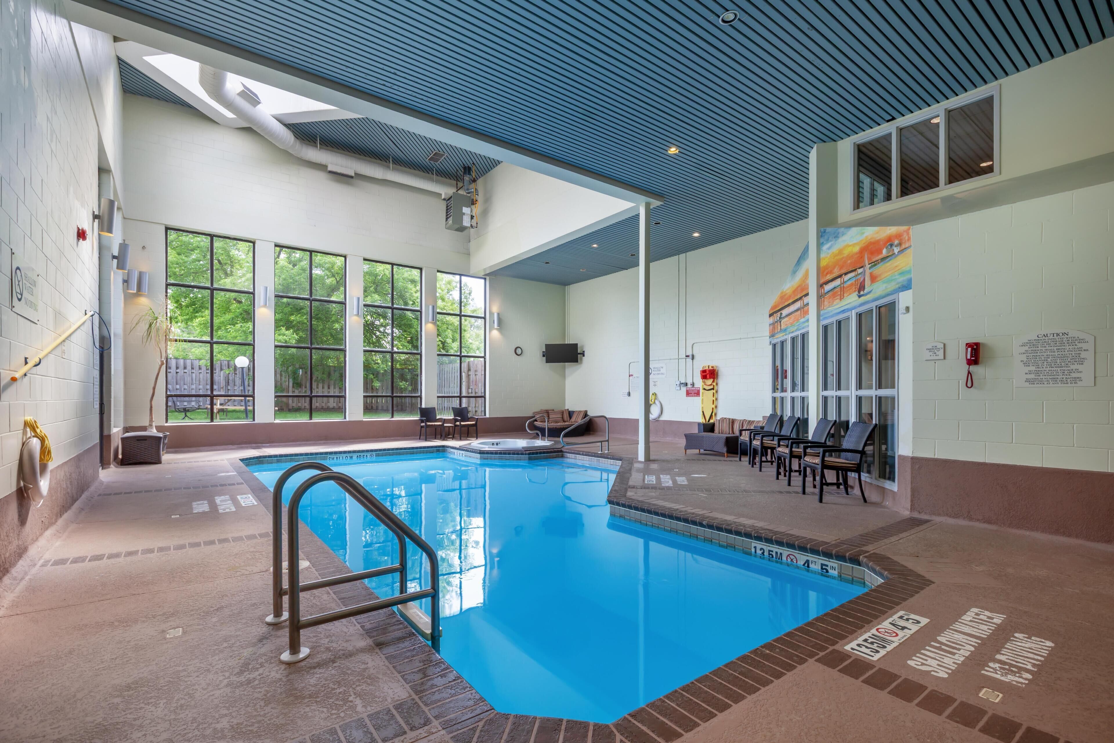 An indoor swimming pool with clear blue water, a tiled deck, and a ceiling with a blue pattern.