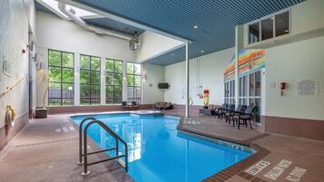 An indoor swimming pool with clear blue water, a tiled deck, and a ceiling with a blue pattern.