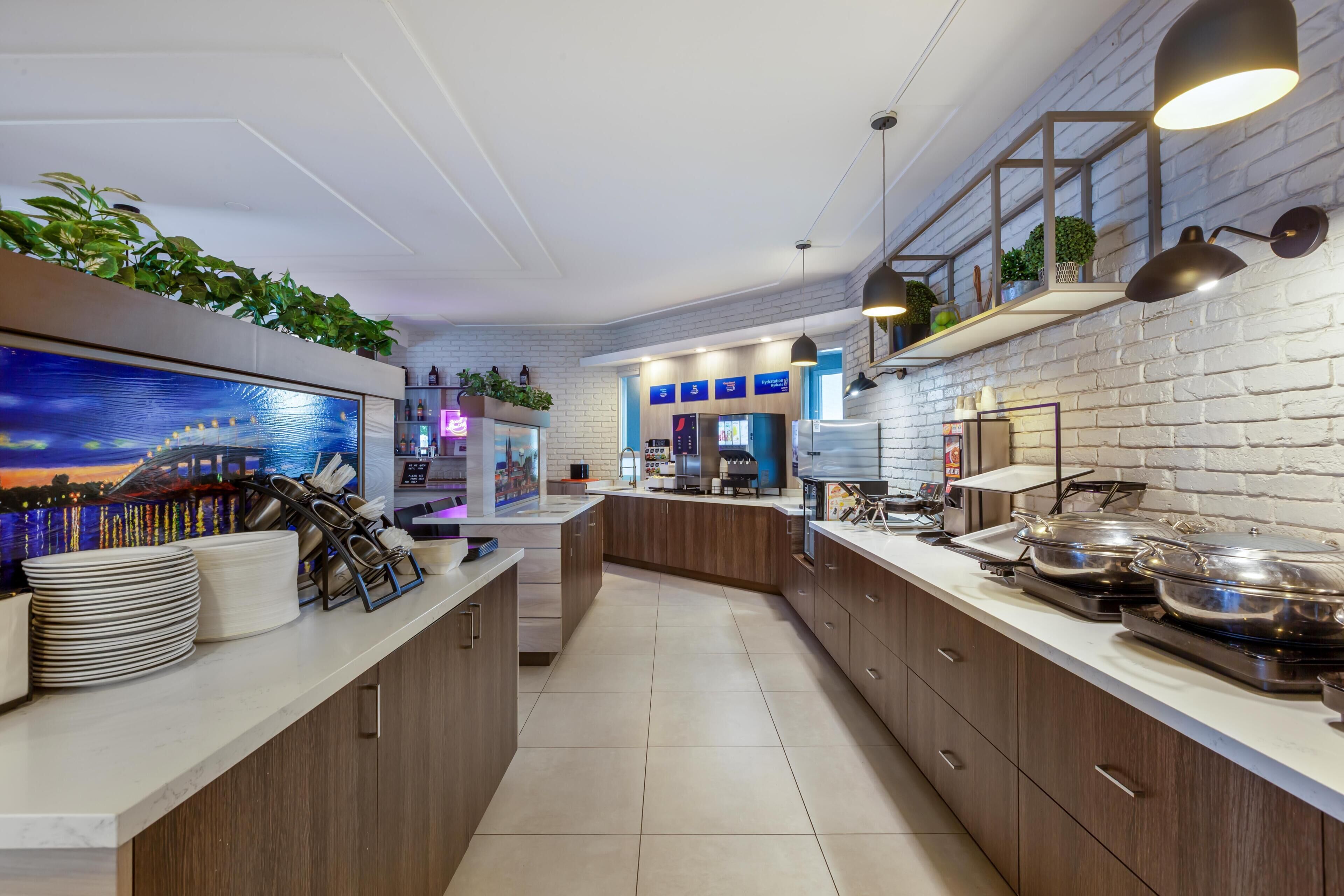 A modern kitchen with wooden cabinets, a large island, and a brick wall.