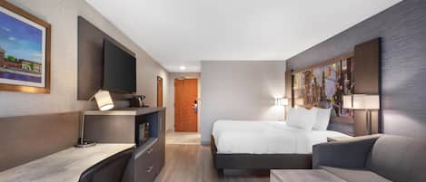 Una habitación de hotel moderna con cama, escritorio, silla y televisor.