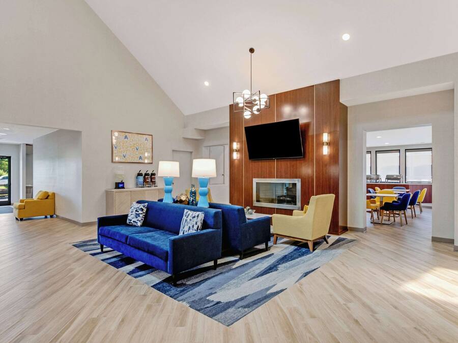 Una sala de estar moderna con un sofá azul, un sillón amarillo y un comedor con sillas amarillas.