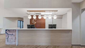 A reception desk with a modern design, featuring a wooden panel wall and a ceiling-mounted light fixture.