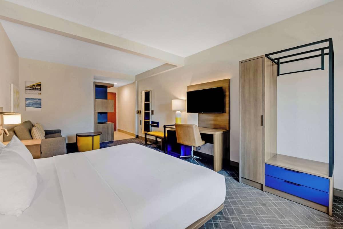 A hotel room with a large bed, a desk with a chair, a TV, and a wardrobe.