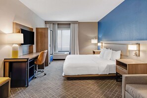 A hotel room with a bed, desk, chair, TV, and a large window. - Comfort Suites Chesapeake - Norfolk (Chesapeake)