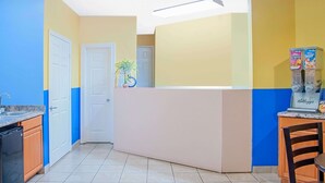 A kitchen with a blue and yellow color scheme, a refrigerator, a sink, and a clock on the wall. - Days Inn by Wyndham Moulton (Moulton)