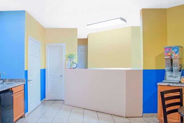 Une cuisine aux couleurs bleu et jaune, avec un réfrigérateur, un évier et une horloge au mur.