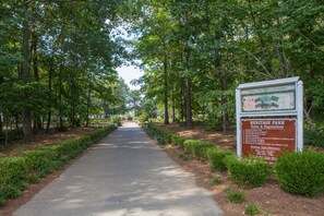 A paved pathway flanked by trees and a signboard with rules and regulations for a park.