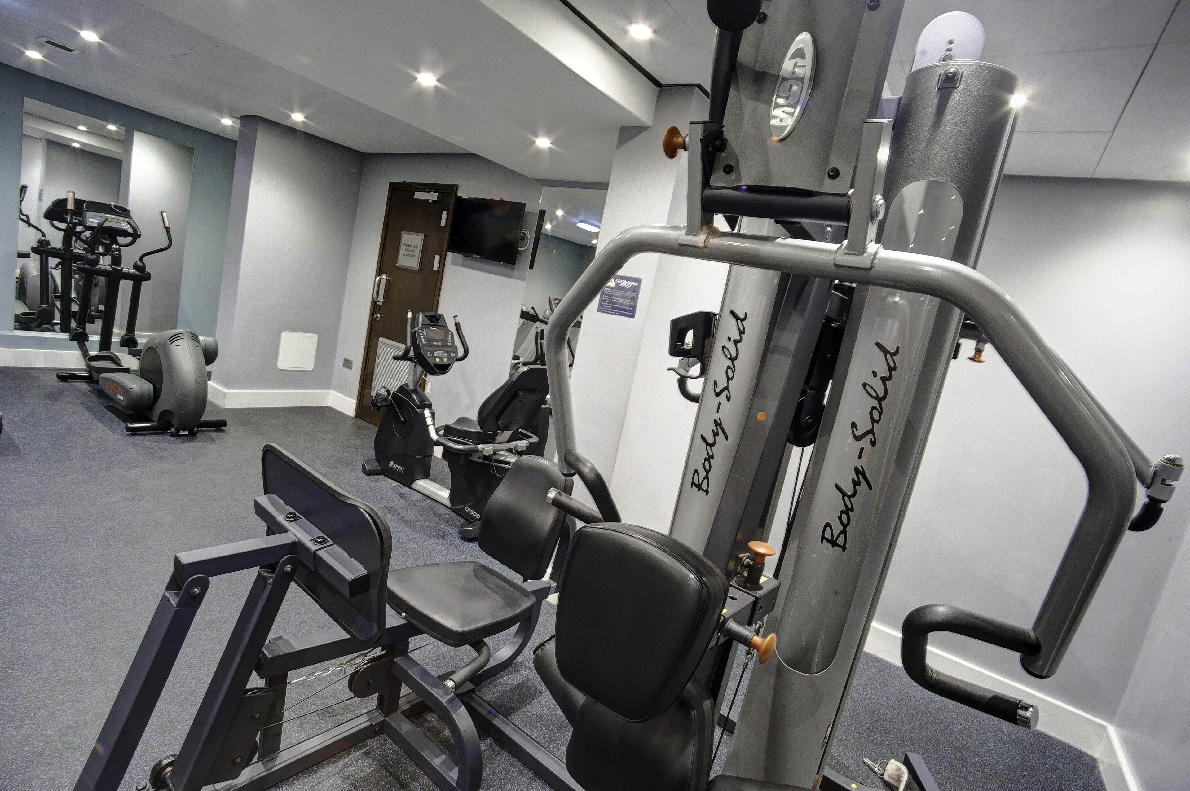 Un gimnasio con diversos equipos de ejercicio, incluyendo una máquina de entrenamiento de fuerza para principiantes.