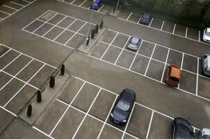 Vista aérea de un estacionamiento con varios coches y algunos árboles.