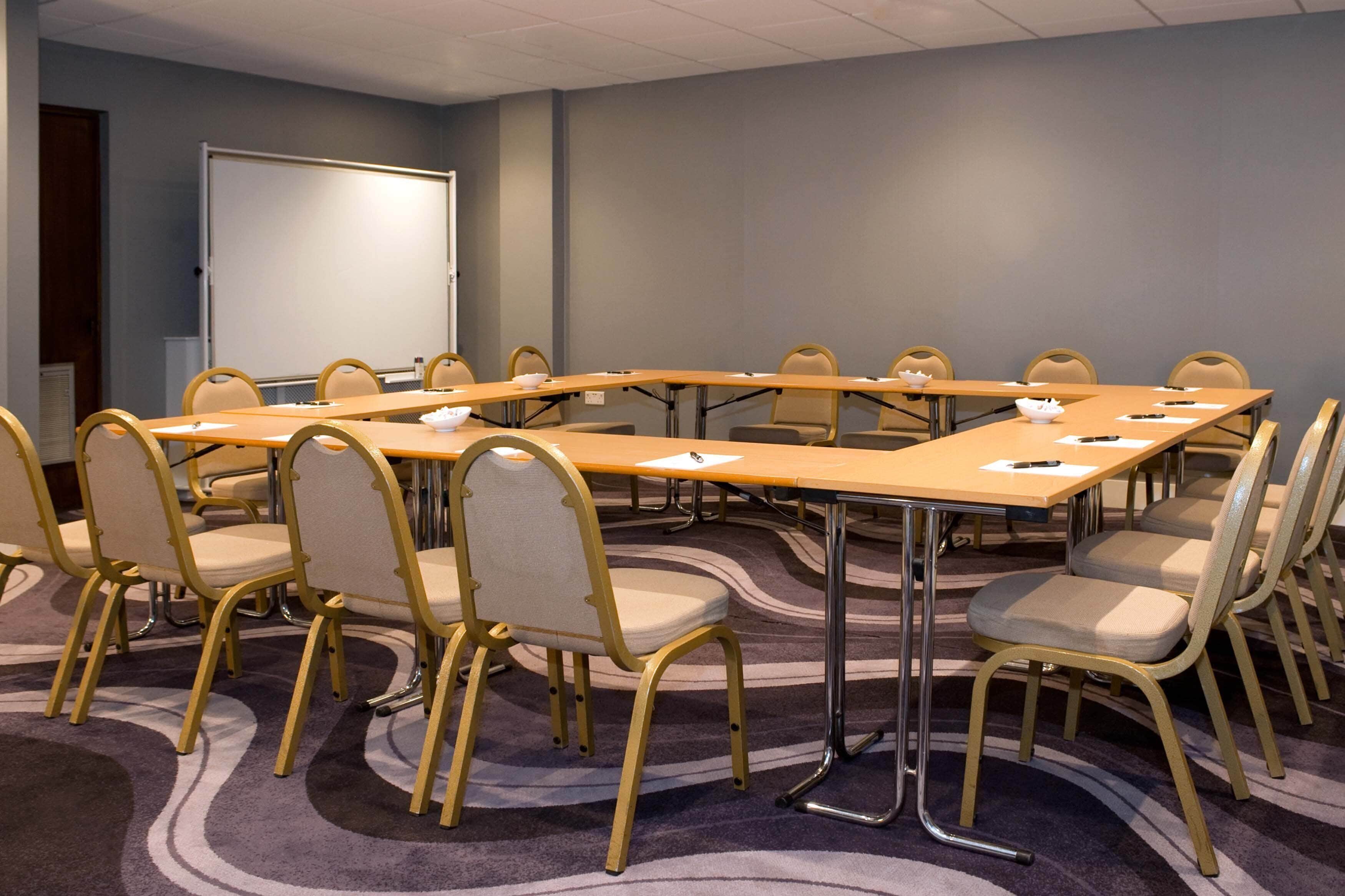 Un salón de conferencias con una gran mesa, varias sillas y una pizarra.