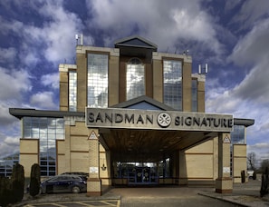 Welcome to Sandman Signature, a modern hotel with a prominent entrance and large windows.
