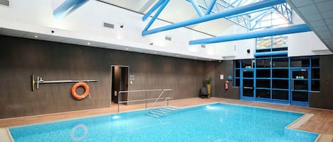 Una piscina cubierta con techo transparente, un flotador salvavidas y una puerta con marcos azules.