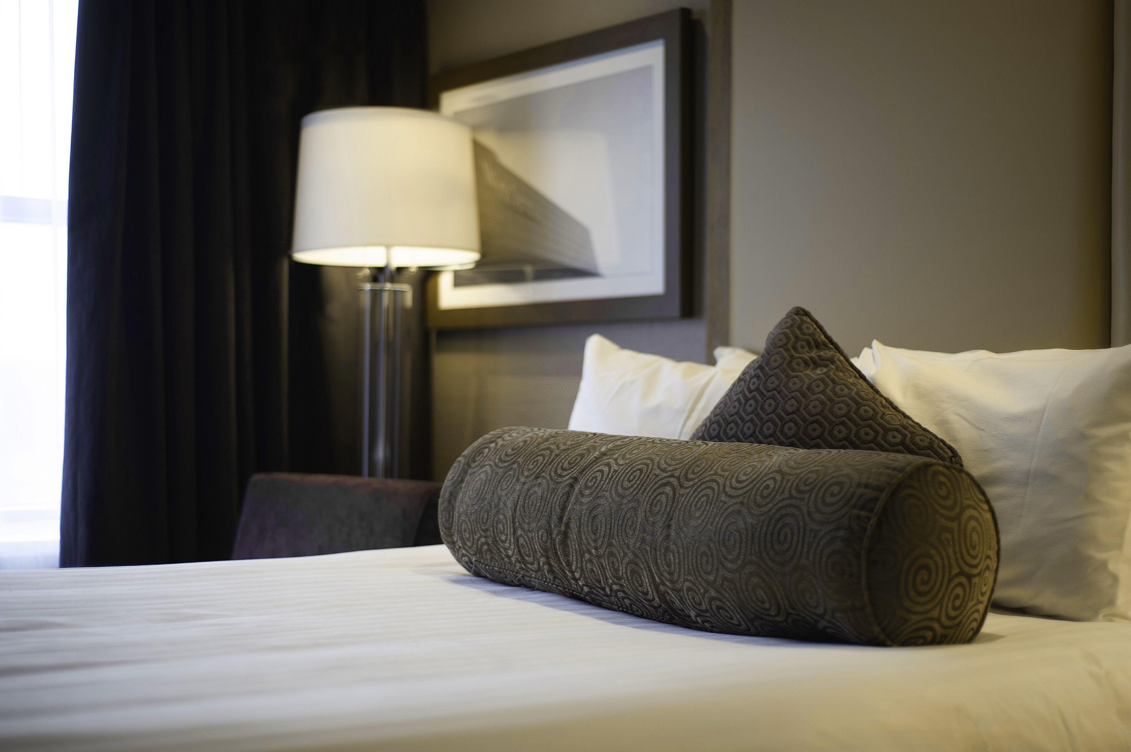 A neatly made bed with patterned pillows and a bedside lamp.