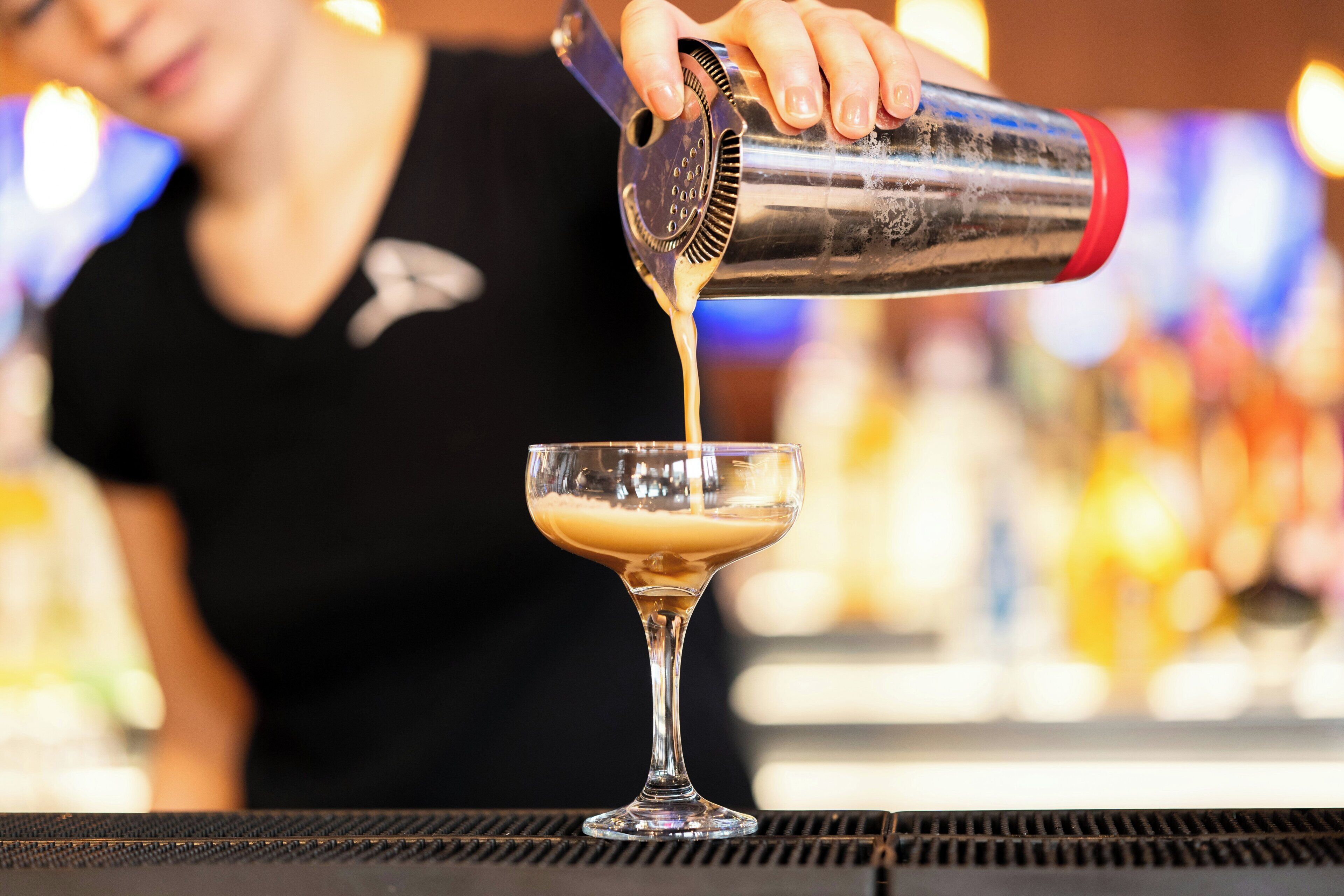 A bartender pouring a drink into a glass.