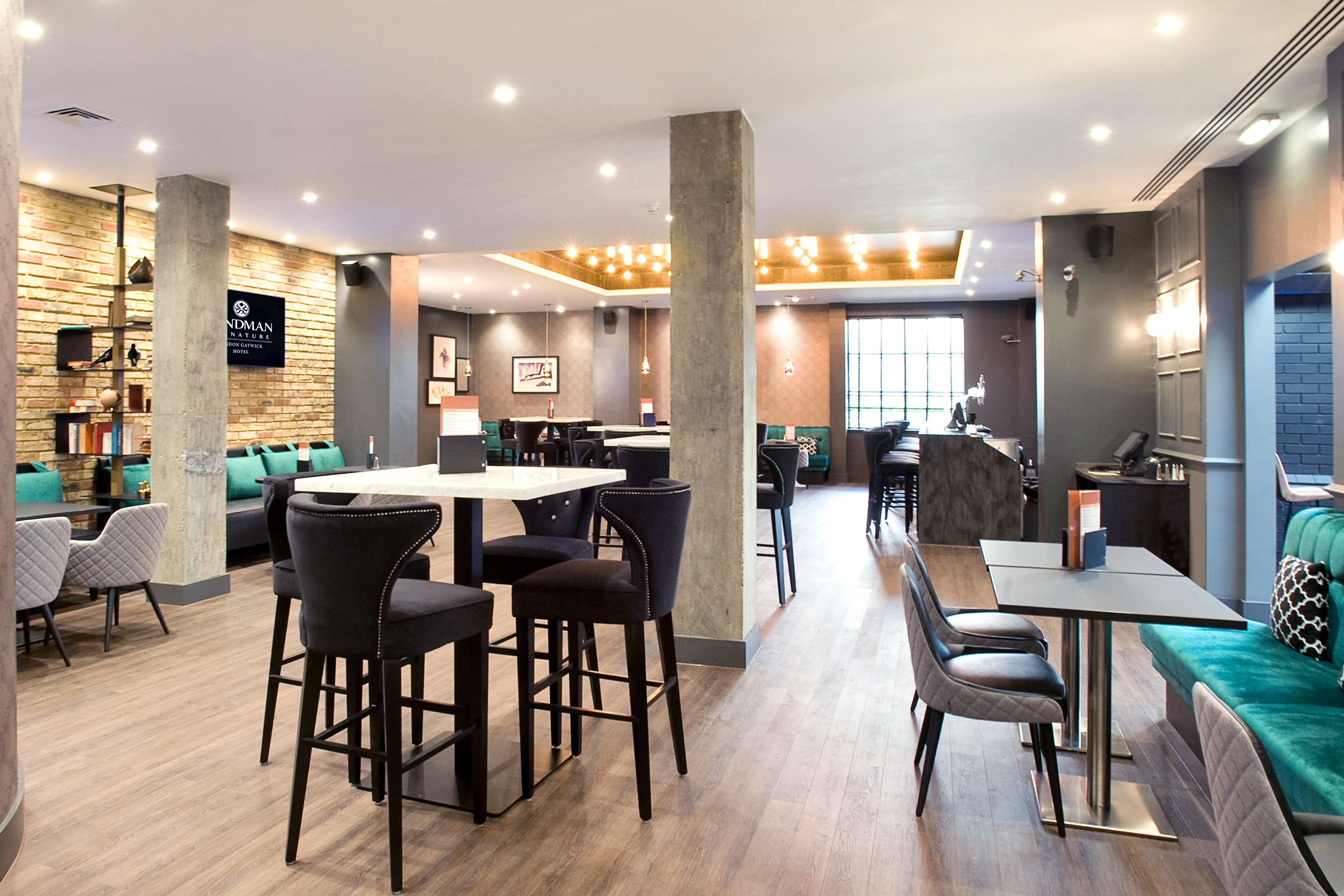 Un moderno vestíbulo de hotel con área de bar, espacios para sentarse y un letrero visible que dice 'NOMAD'.