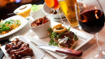 A variety of dishes including wings, a burger, and a salad, along with different types of drinks.